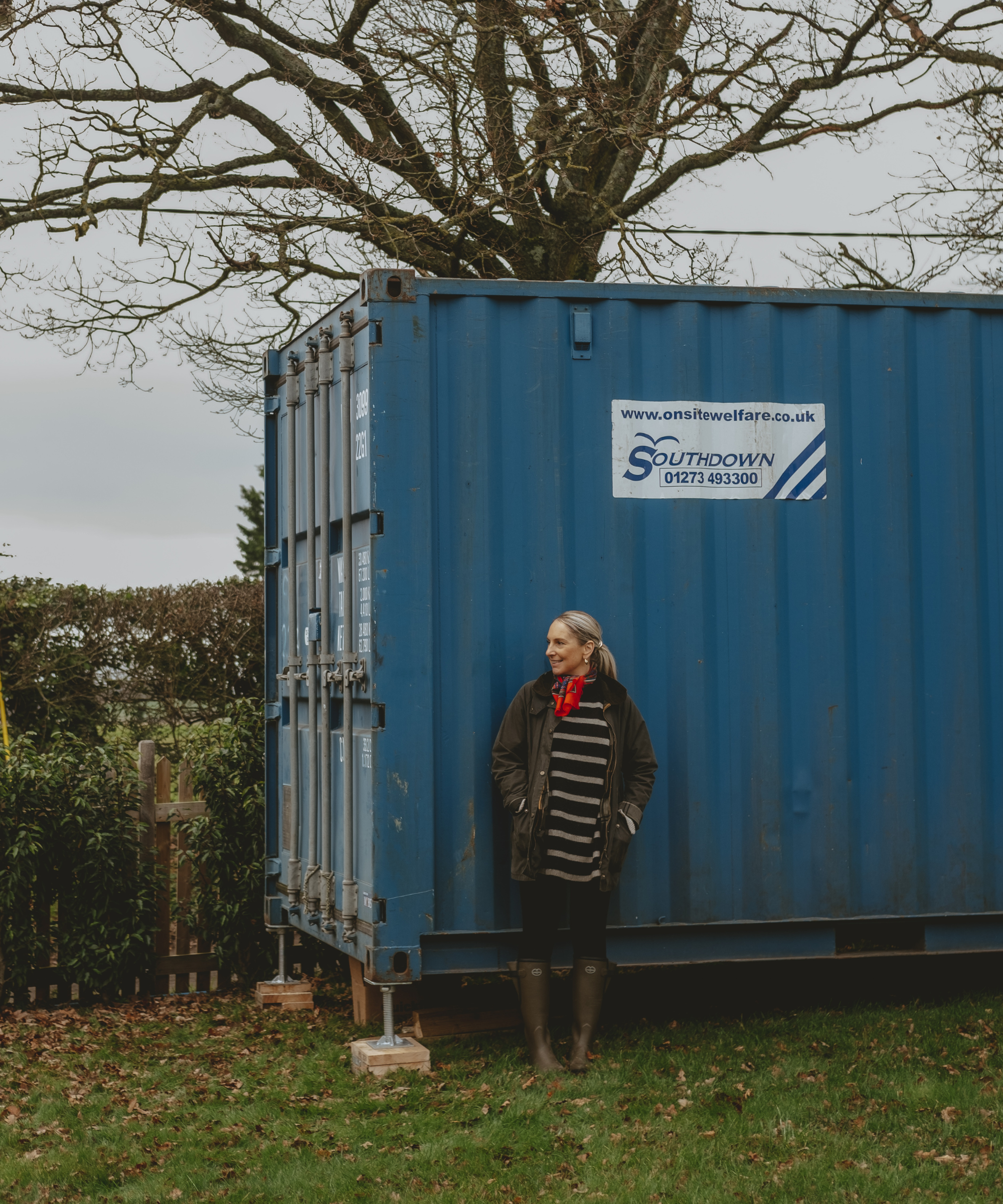 Abbie standing outside the blue shipping container before it was renovated