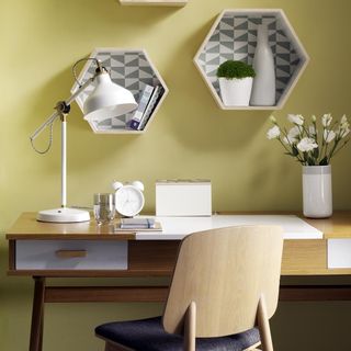 Yellow home office hexagonal display sheves wooden desk, lamp.