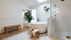 A fiddle leaf fig stans behind a bathtub in a chic bathroom