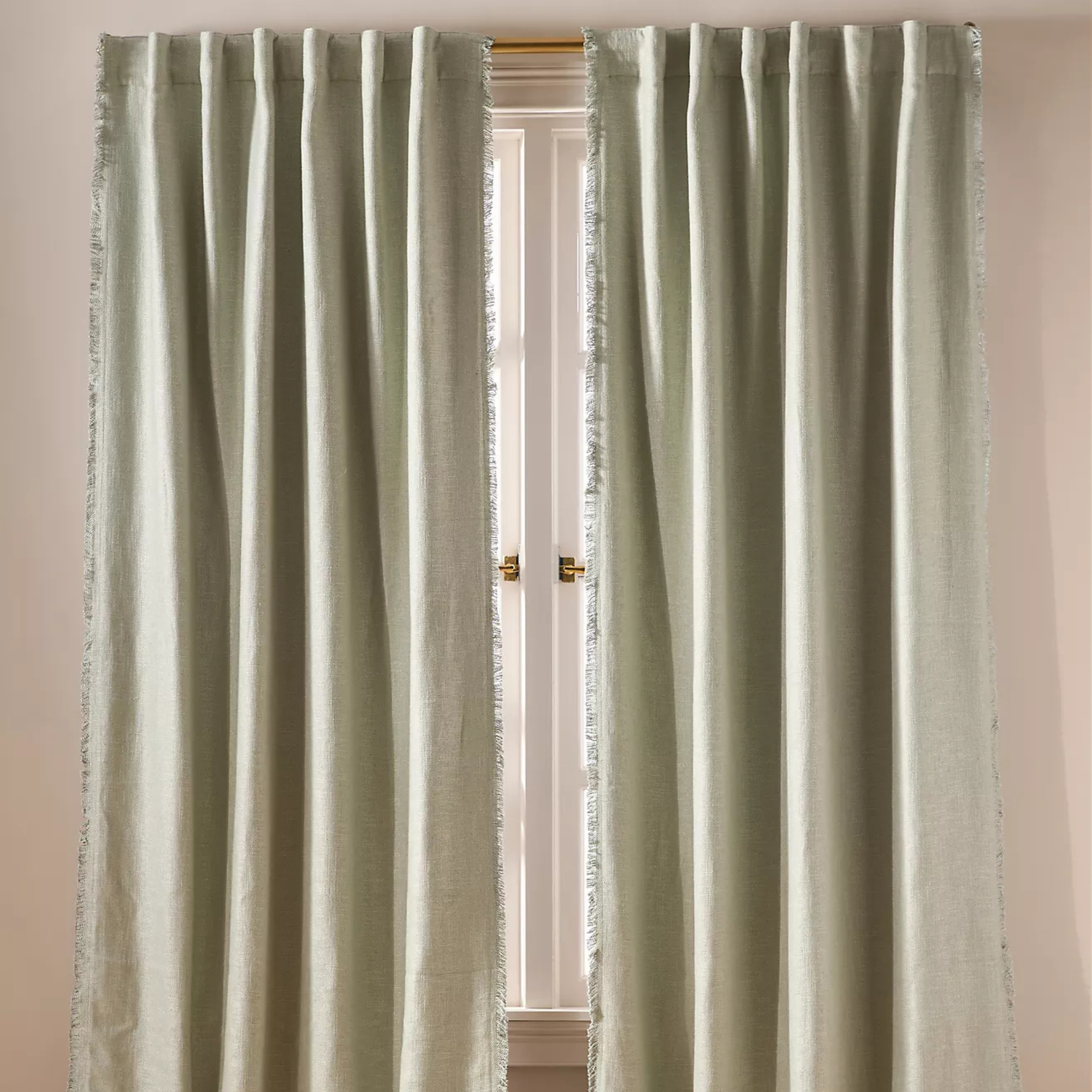 Sage green linen curtains hanging in front of a double-paned window