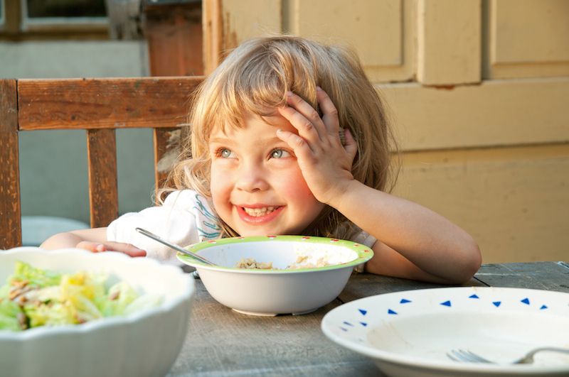 A little girl eats a meal.