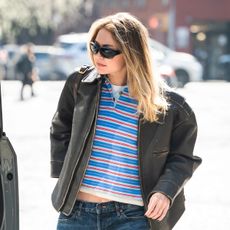 Gigi Hadid wearing a leather jacket, polo shirt, low-rise jeans, and ruched loafers in NYC