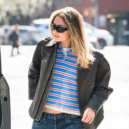 Gigi Hadid wearing a leather jacket, polo shirt, low-rise jeans, and ruched loafers in NYC