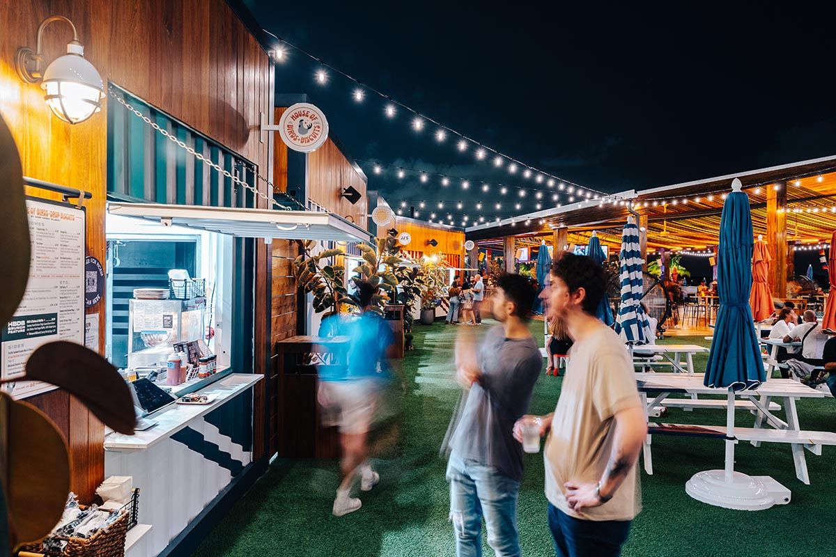 Guests enjoying Miami&#039;s Regatta Grove, an outdoor Waterfront entertainment venue at night.