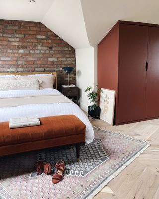 orange and white bedroom in loft space, exposed brick wall, orange footstool and wardrobe