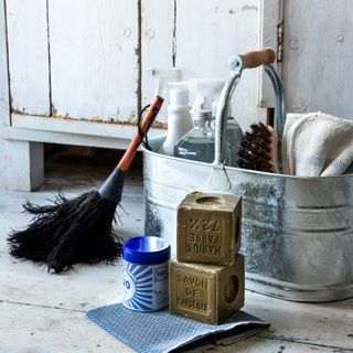 Detail of a galvanised steel caddy used to store cleaning equipment with a feather duster propped against it
