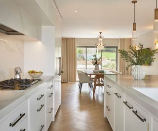 A white kitchen with marble countertops and black hardware