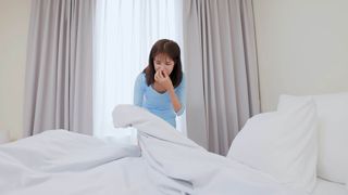 A woman holding her nose as she changes the bedding