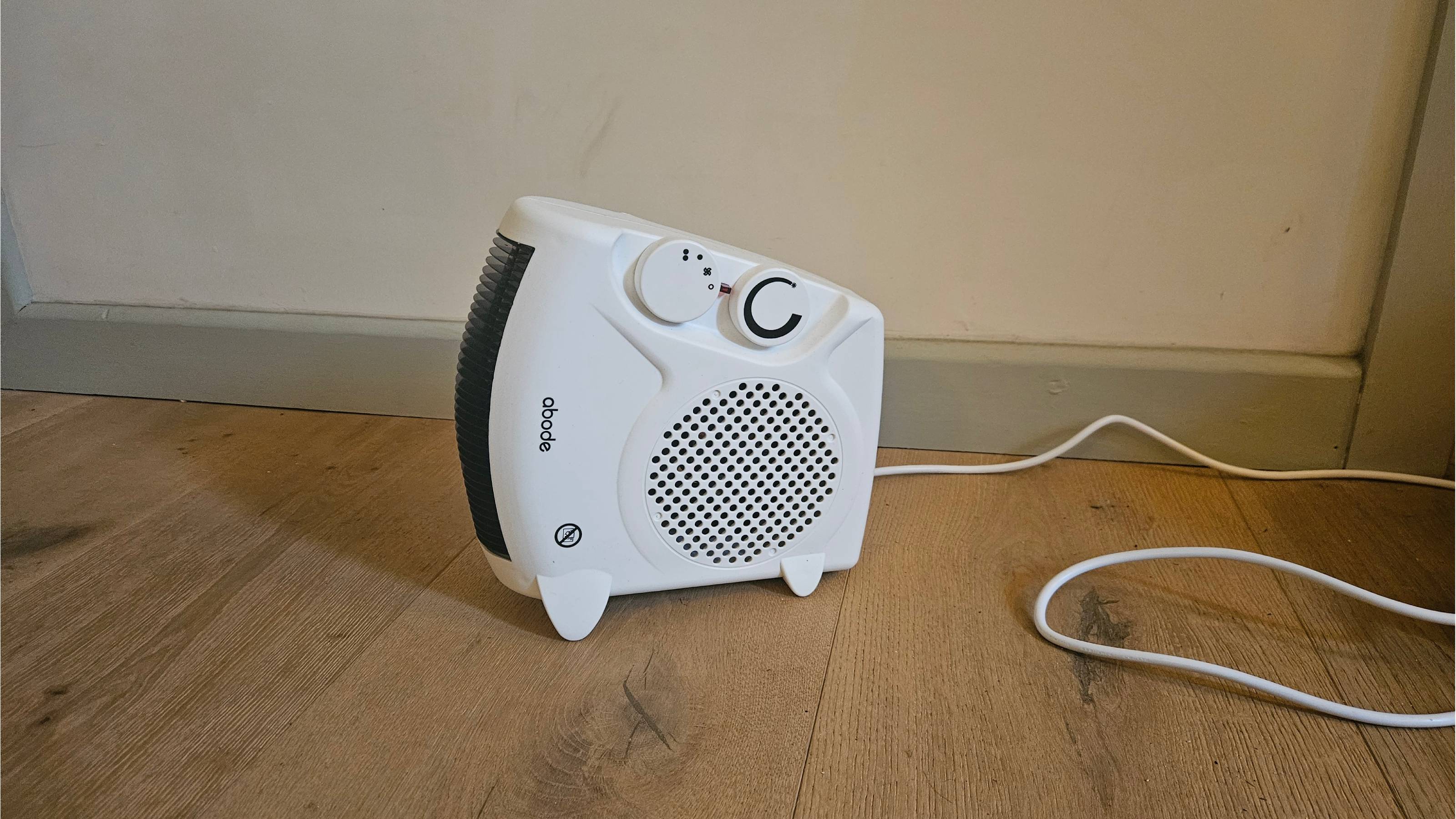 white fan heater on its side in front of white wall on wood floor