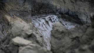 A layer of permafrost melts, exposing the rocky substrate underneath.