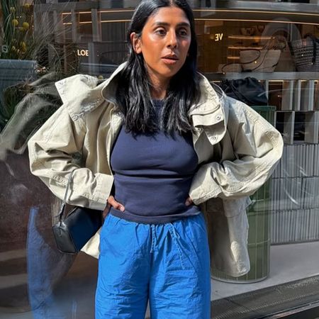 Woman in blue pants, a tank top and a beige jacket