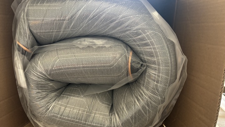The inside of a shipping box containing a rolled-up and vacuum-packed EGOHOME Black 12" Mattress.