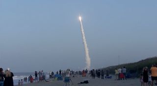 Beach-goers watch a United Launch Alliance Atlas V rocket launch into space carrying two military satellites on the AFSPC-11 mission. Liftoff occurred at 7:13 p.m. EDT on April 14, 2018.