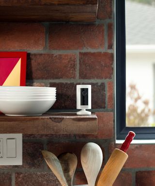 Ring Indoor Cam on a kitchen shelf with an exposed brick wall behind it