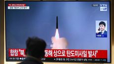 A man watches a missile launch on a TV screen