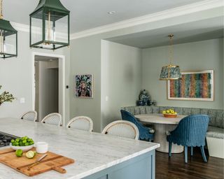 kitchen-dining room with blue cabinets, light green walls and colorful artwork on wall