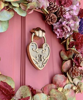 Padlock heart door knocker with floral decorative wreath on pink door frame by Gipsy Hill Hardware