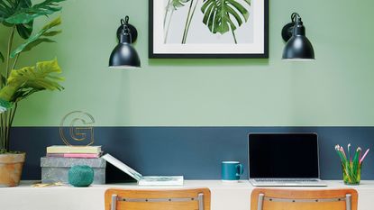 Home office with two toned green painted walls, botanical print and two wall lights