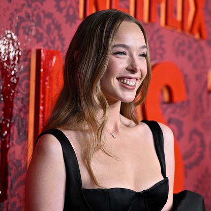 ella beatty smiles posing on a red carpet wearing a black long gown at the premiere of monster the lizzie borden story 
