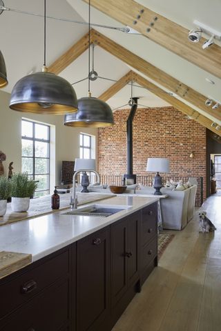 A farmhouse style kitchen with high vaulted ceiling and large brass pendant lights