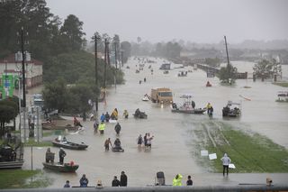 People walk down a flooded street as they evacuate their homes after the area was inundated with flooding from Hurricane Harvey on August 28, 2017 in Houston, Texas.