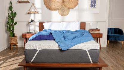 Bedroom with a wooden bed, showing mattress topper and blue quilt