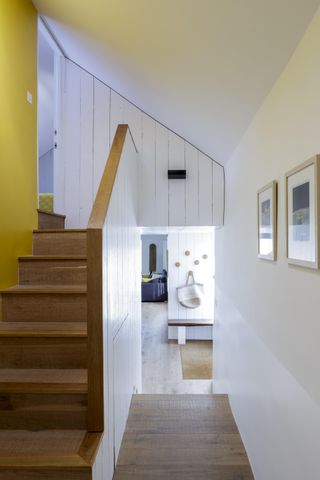 A modern hallway with a stairwell to the left alongside a bright yellow feature walland corridor to the right
