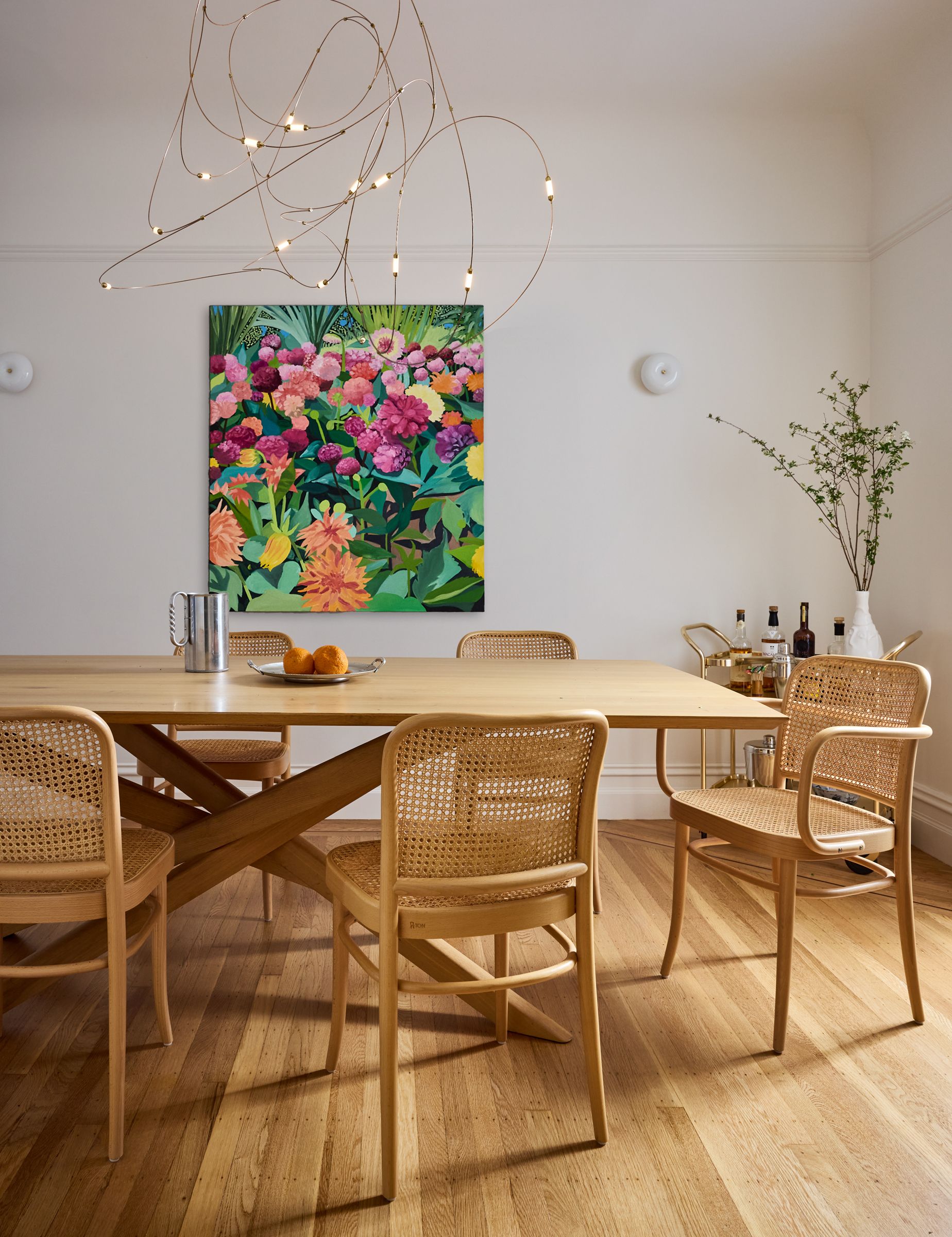A white dining room with mid tone wood flooring and cane dining chairs