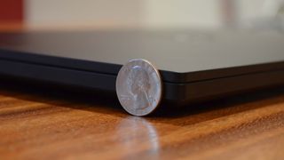 Sidan av Razer Blade 15 (2022) med ett mynt som står lutat mot laptopen, för att visa dess tjocklek.