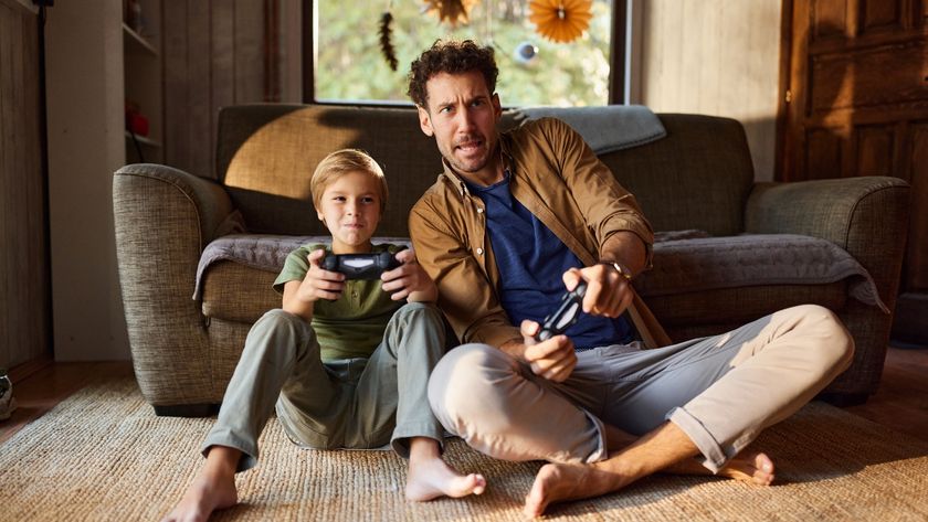 Man and son sitting on the floor in front of the couch with controllers playing video games