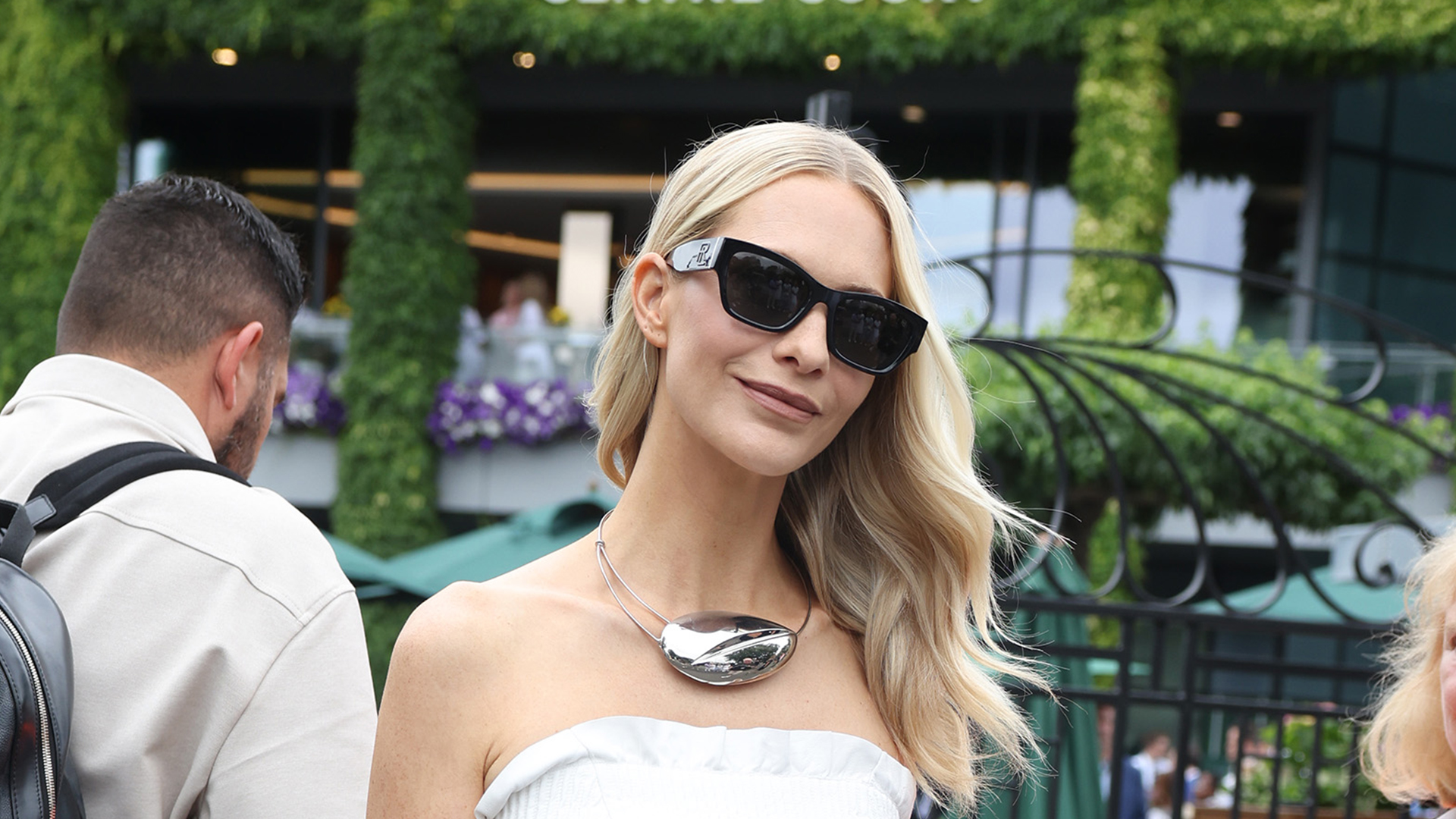 Cate Blanchett wearing a white tube top, black wide-leg pants, sunglasses, and collar pendant necklace
