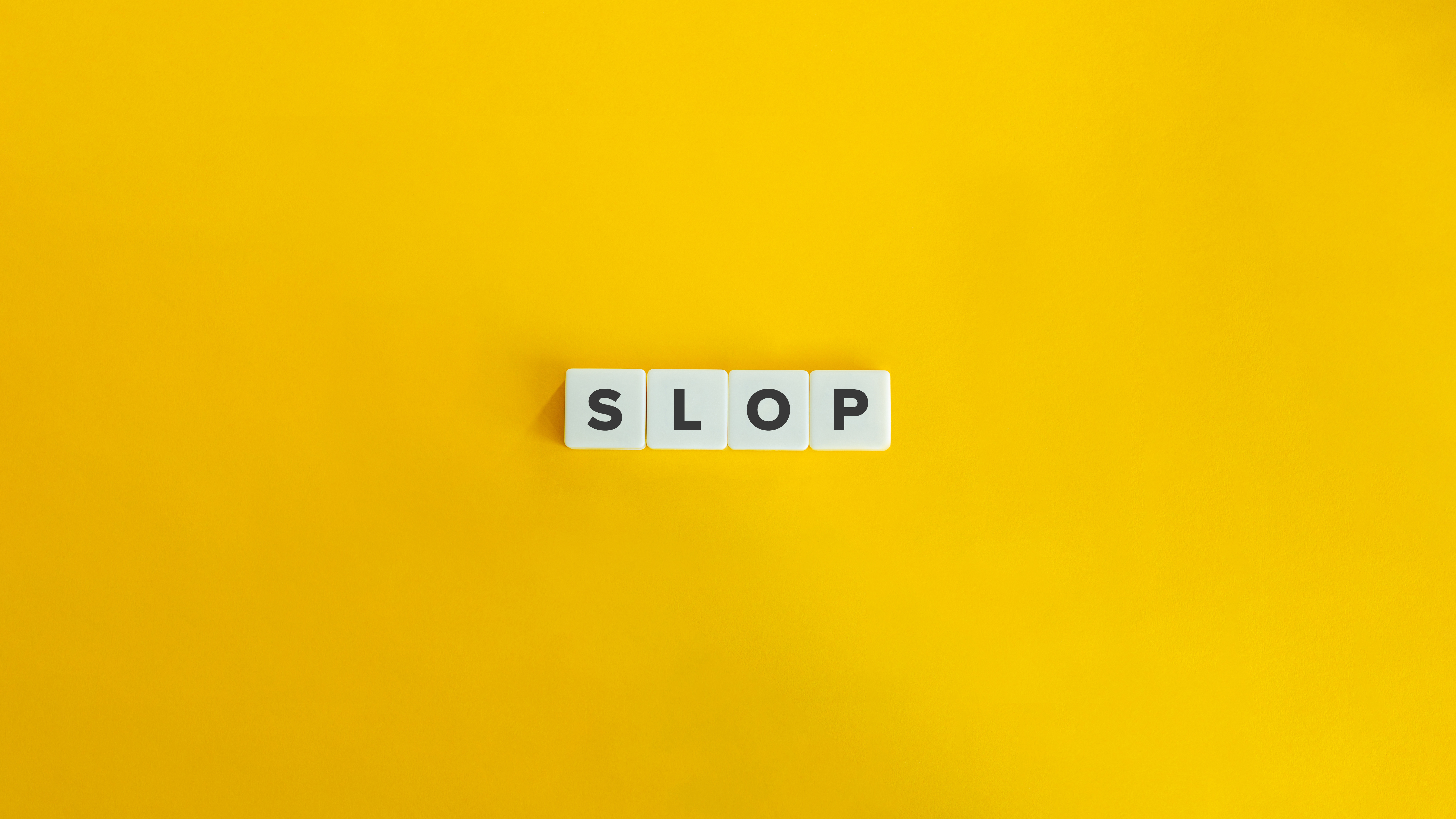 Letter game tiles spell out the word "slop" on a yellow background