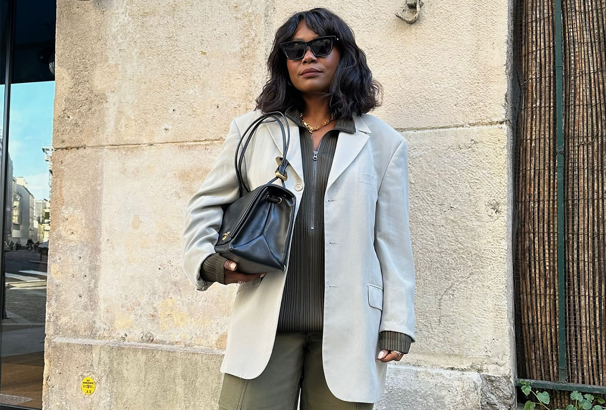 French woman wearing a blazer over a pleated zip-up and green cargo pants.