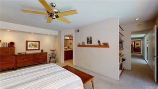 A dated living room with a beige walls, wooden furniture and a fan