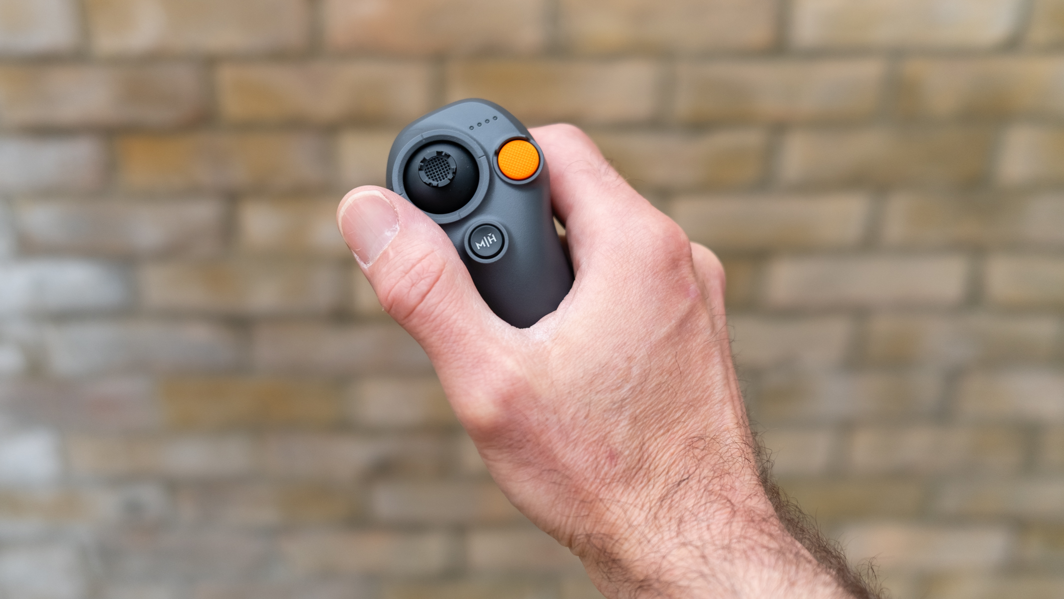 DJI RC Motion 3 Controller held in a man's hand with a defocused wall in the background