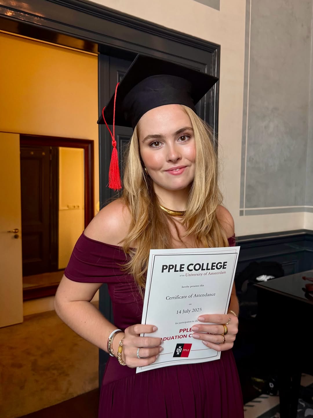 Princess Catharina-Amalia wearing a burgundy dress and a graduation cap