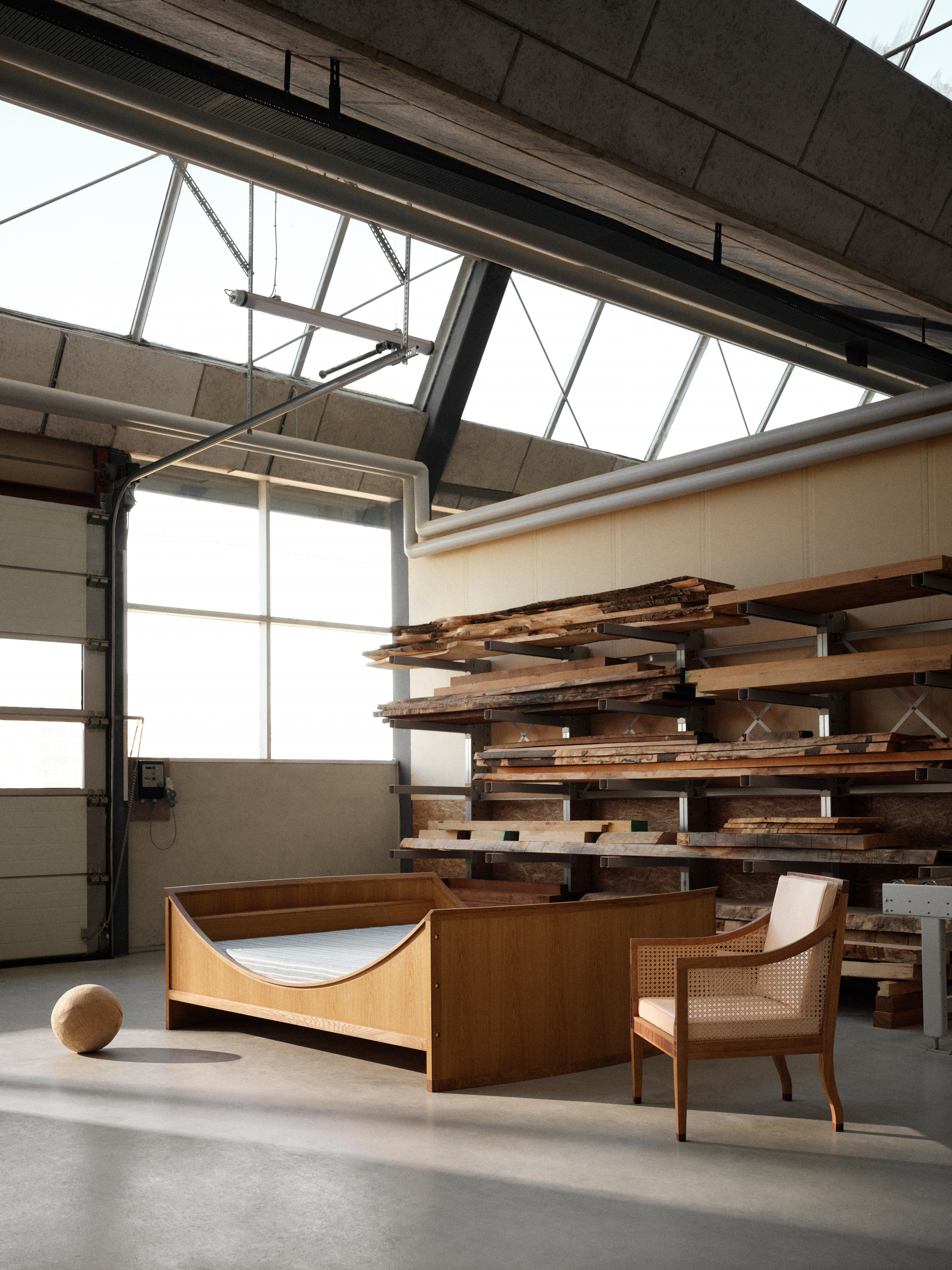 A series of wooden furniture pieces sits in an industrial warehouse, bathing in sunshine.