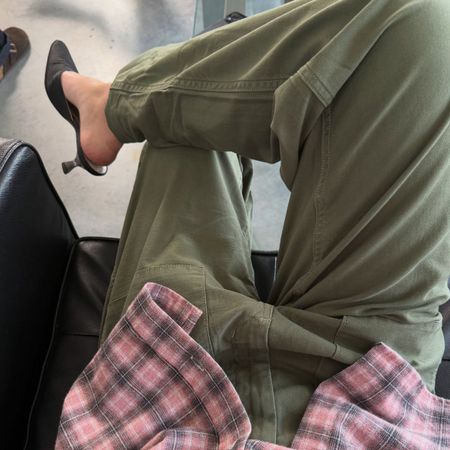 A creator wearing a stylish outfit consisting of green cargo trousers and a pink checked shirt