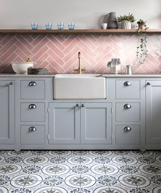 Playful pastel galley kitchen with pink backsplash tiles, soft gray cabinets and tonal, patterned floor tiles