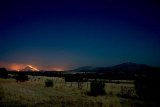 Guide Peak is in flames from the controlled burn on April 17. The two peaks of McDonald Observatory, Mount Fowlkes and Mount Locke, are to the right and far right, respectively. The domes of the 30-foot (9.1-m) Hobby-Eberly, Harlan J. Smith and Otto Struv