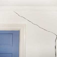 crack in wall near a blue door