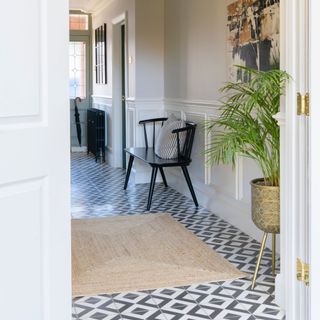 Large home hallway with black and white diamond tile flooring with a jute rug on top