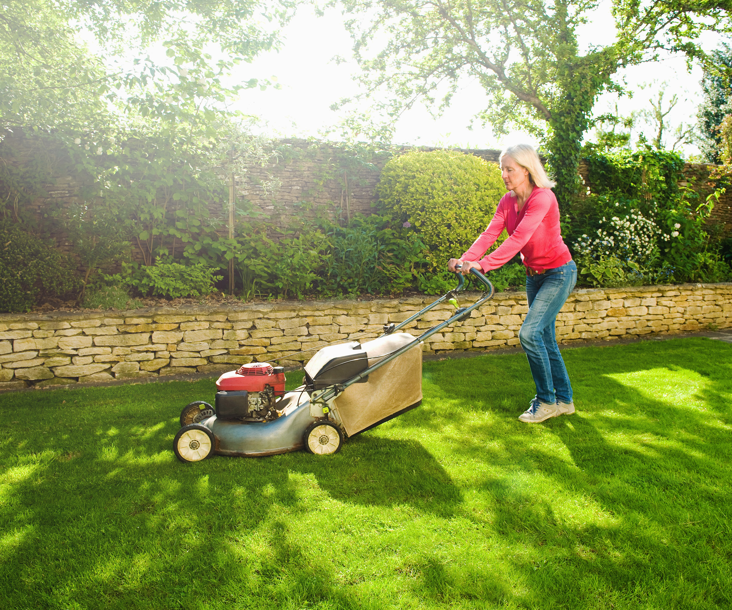 Woman mowing a lawn in summer