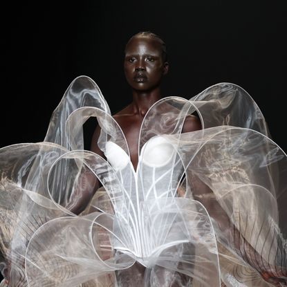 A runway model wearing a white sculptural gown