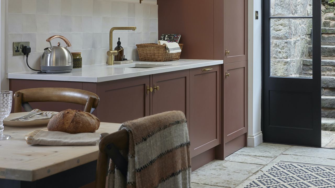 Brown shaker kitchen with white worktops in country home