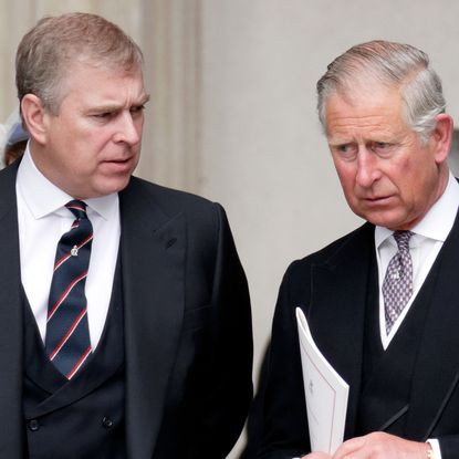 Prince Andrew looks at King Charles, as both royal brothers wear suits in 2012