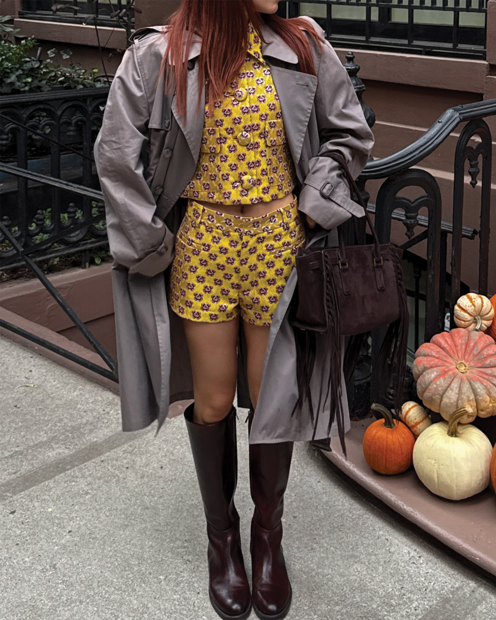 Who What Wear Editor in Residence Kristina Ang wearing a yellow set with a gray trench coat and knee-high boots.