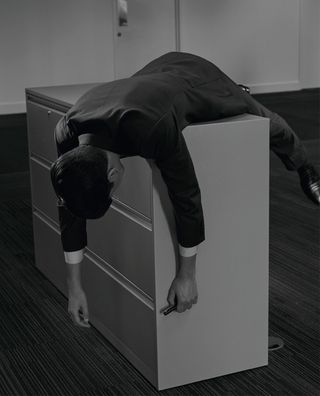 man in suit slumped over filing cabinet