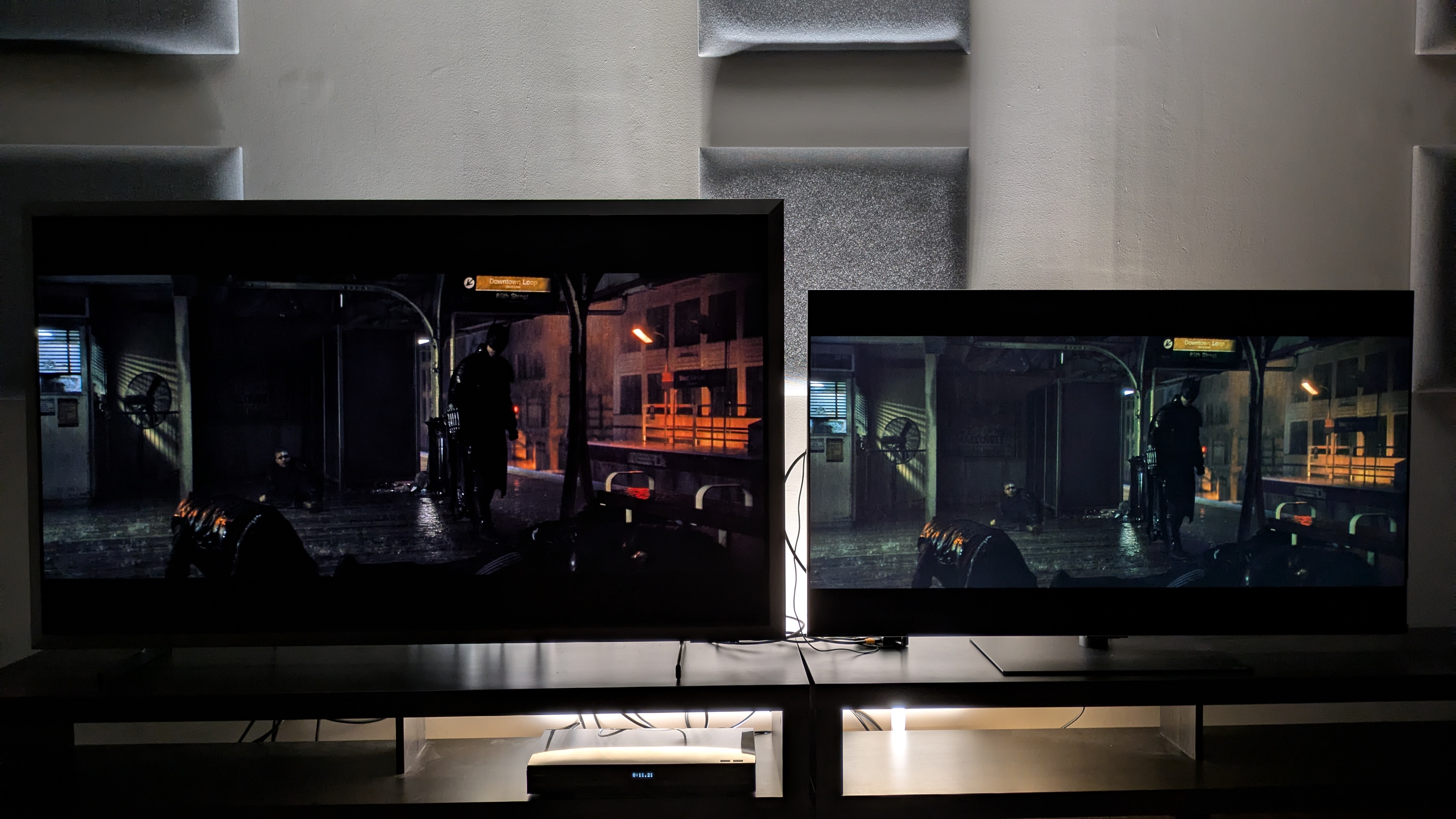 Samsung S99H (left) vs LG G6 (right) showing Batman on a subway platform from The Batman. The S99H showcases deeper blacks but does show some black crush while the LG G6 looks too bright