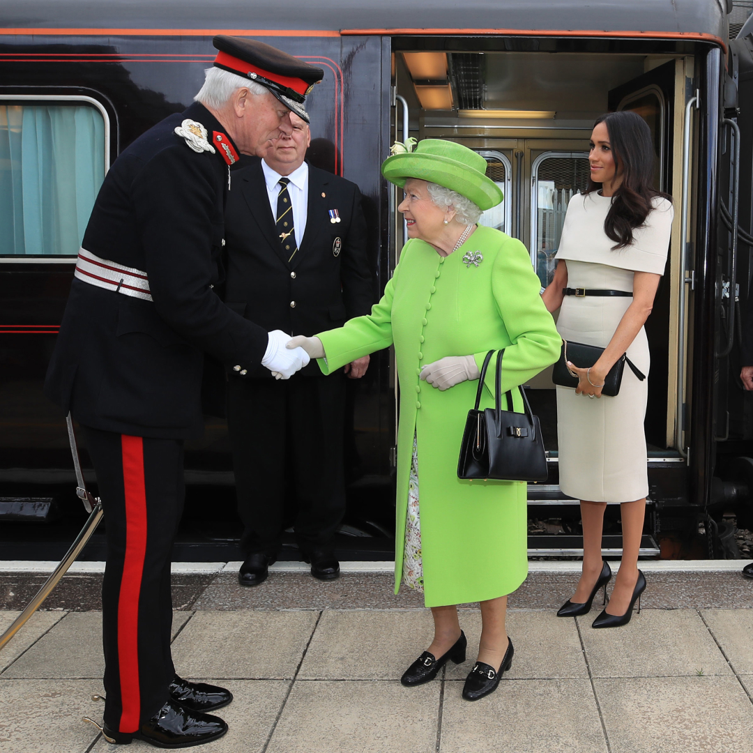 Queen Elizabeth and Meghan Markle standing next to the royal train